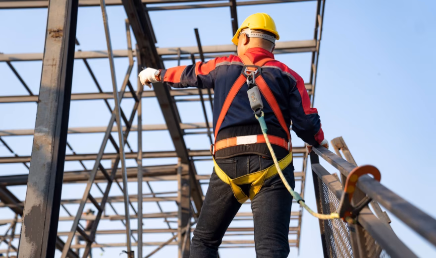 An employee is performing work at height using fall protection on a steel structure.