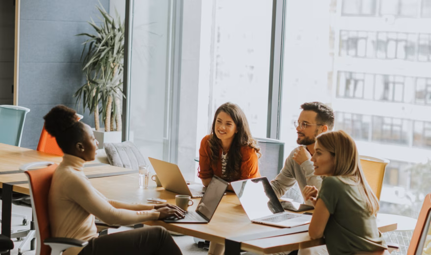 Employees discuss their work and processes during a meeting in a modern office setting.