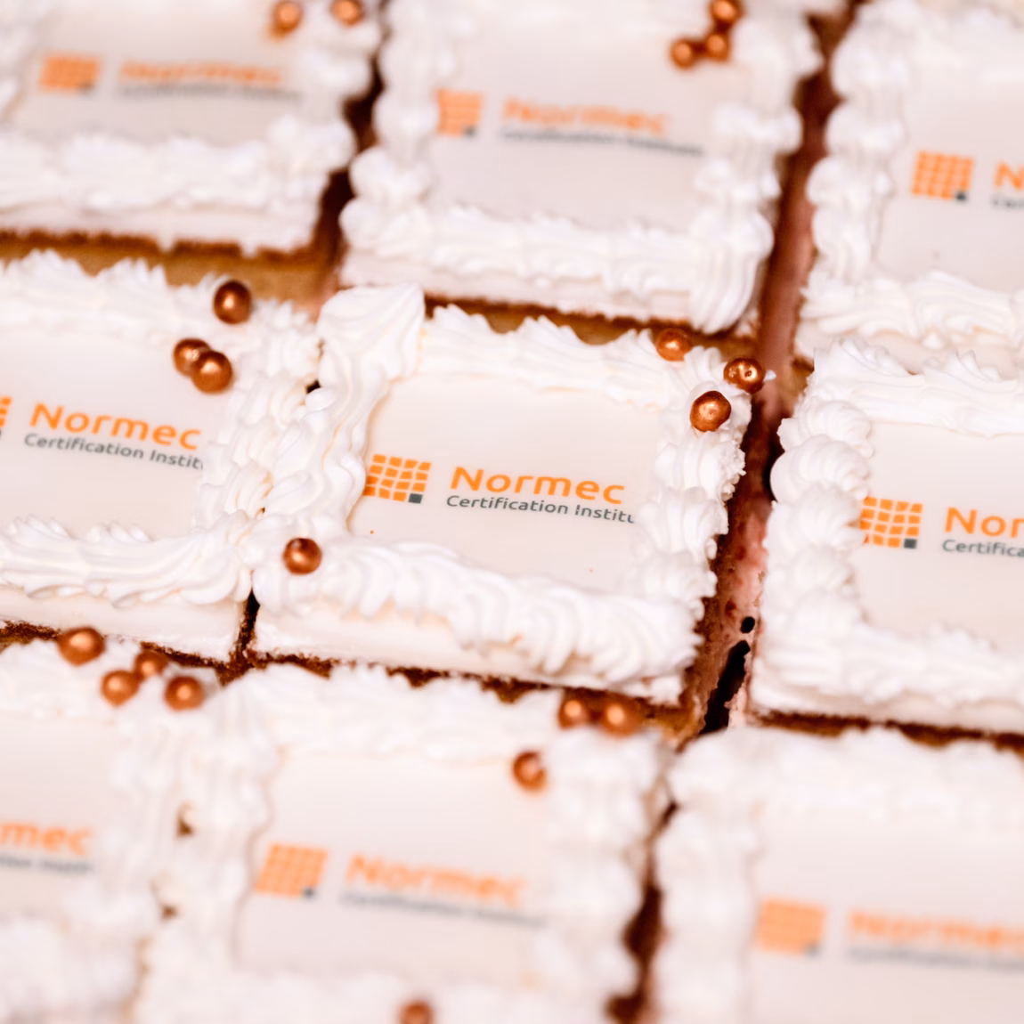 Cakes with a logo are presented during a gathering or celebration within the organization.