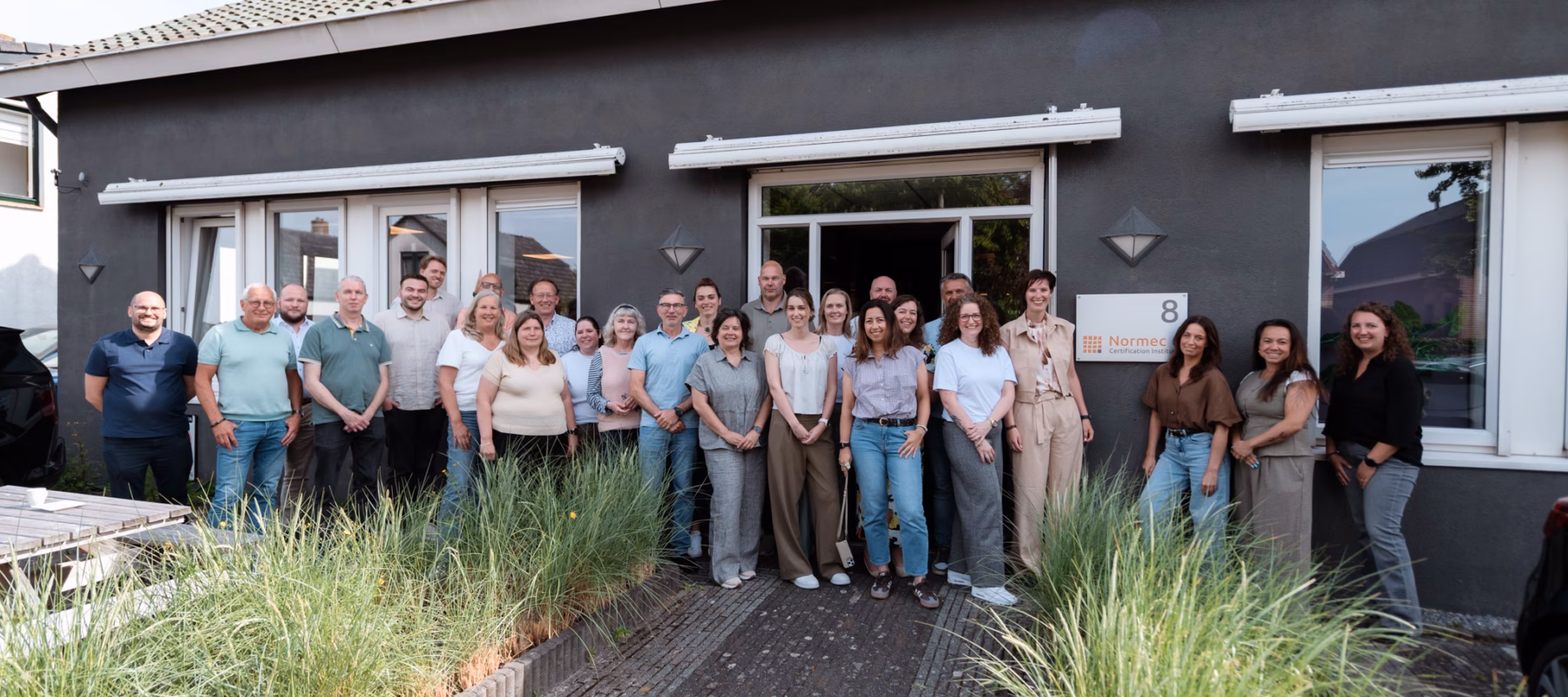 A group of employees is standing together in front of an office building during a team-building event.