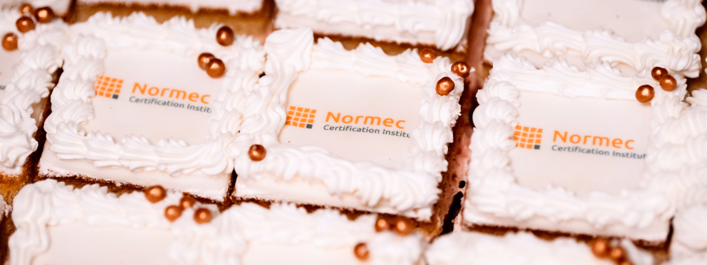 Cakes with a logo are presented during a gathering or celebration within the organization.