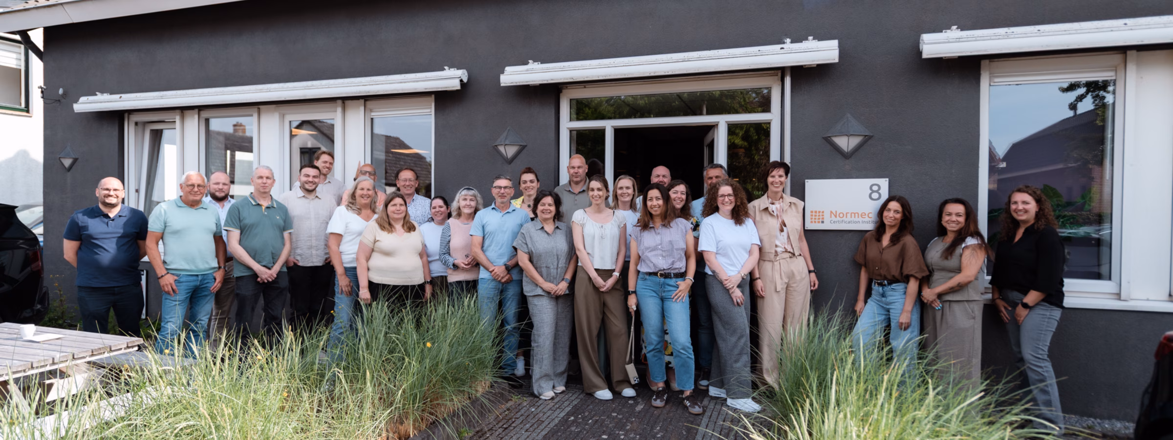 A group of employees is standing together in front of an office building during a team-building event.