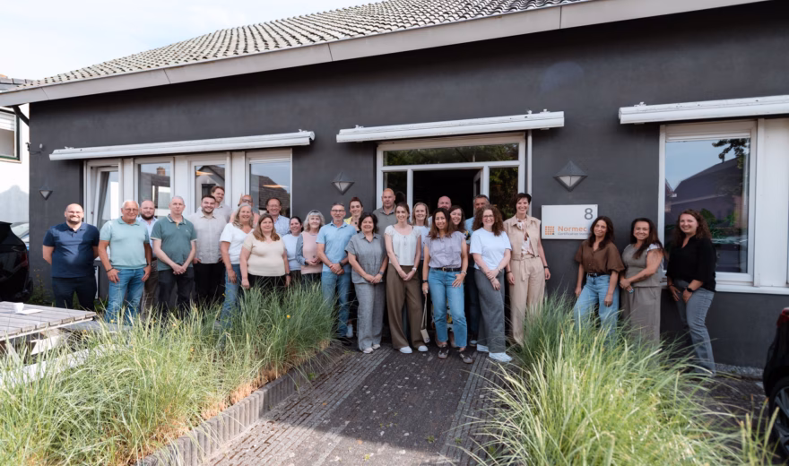 A group of employees is standing together in front of an office building during a team-building event.