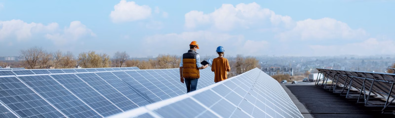 Deux employés vérifient une installation de panneaux solaires sur un toit.
