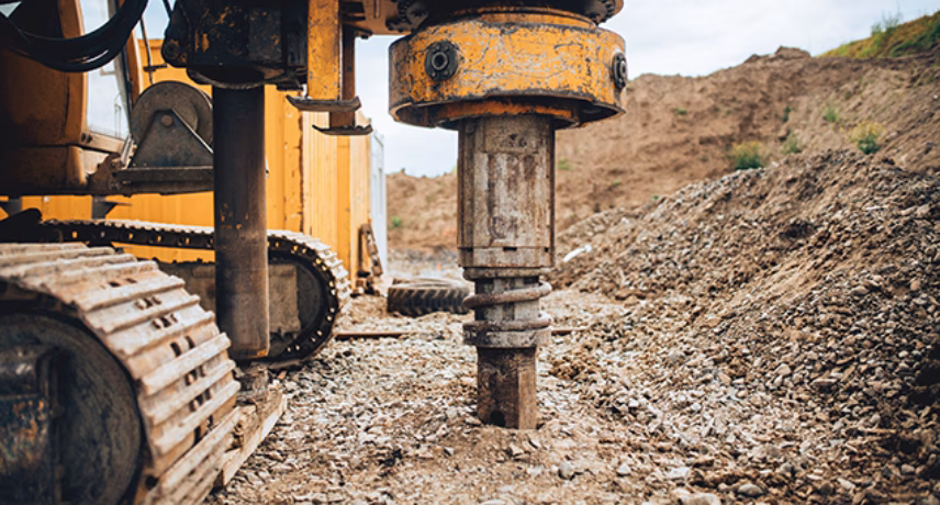 Eine Erdbohrmaschine führt auf einer Baustelle Bohrarbeiten für Fundamentarbeiten oder Bodenuntersuchungen durch.