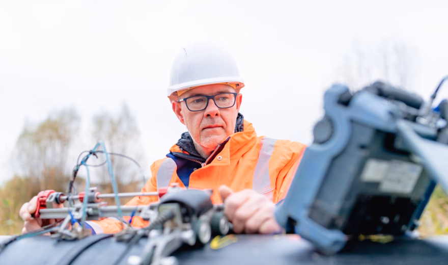 An employee checks technical measurement data during an inspection using specialized equipment in the field.