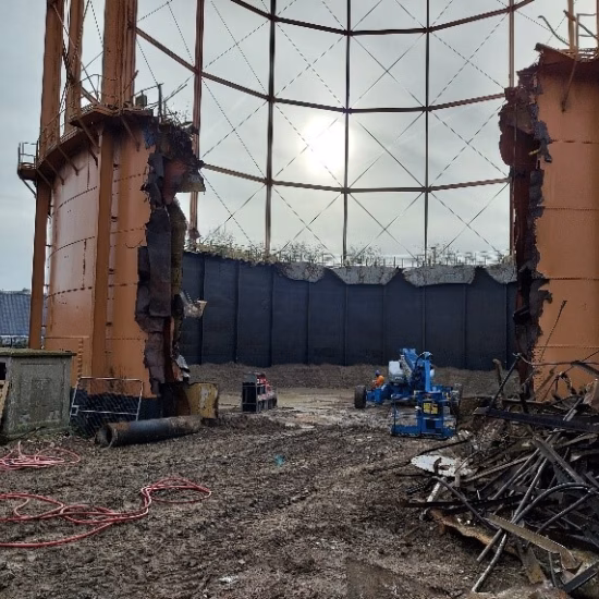 An industrial storage tank is being partially dismantled during demolition and disassembly work on site.