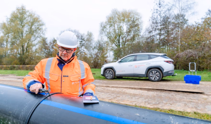 An employee is inspecting a pipe using specialized measuring equipment during an on-site inspection.