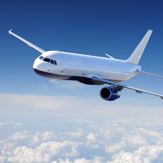 A passenger plane is flying at cruising altitude above a layer of clouds.