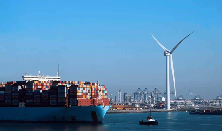 Ein Containerschiff fährt an einem Hafen vorbei, in dem Logistik und nachhaltige Energie aufeinandertreffen.
