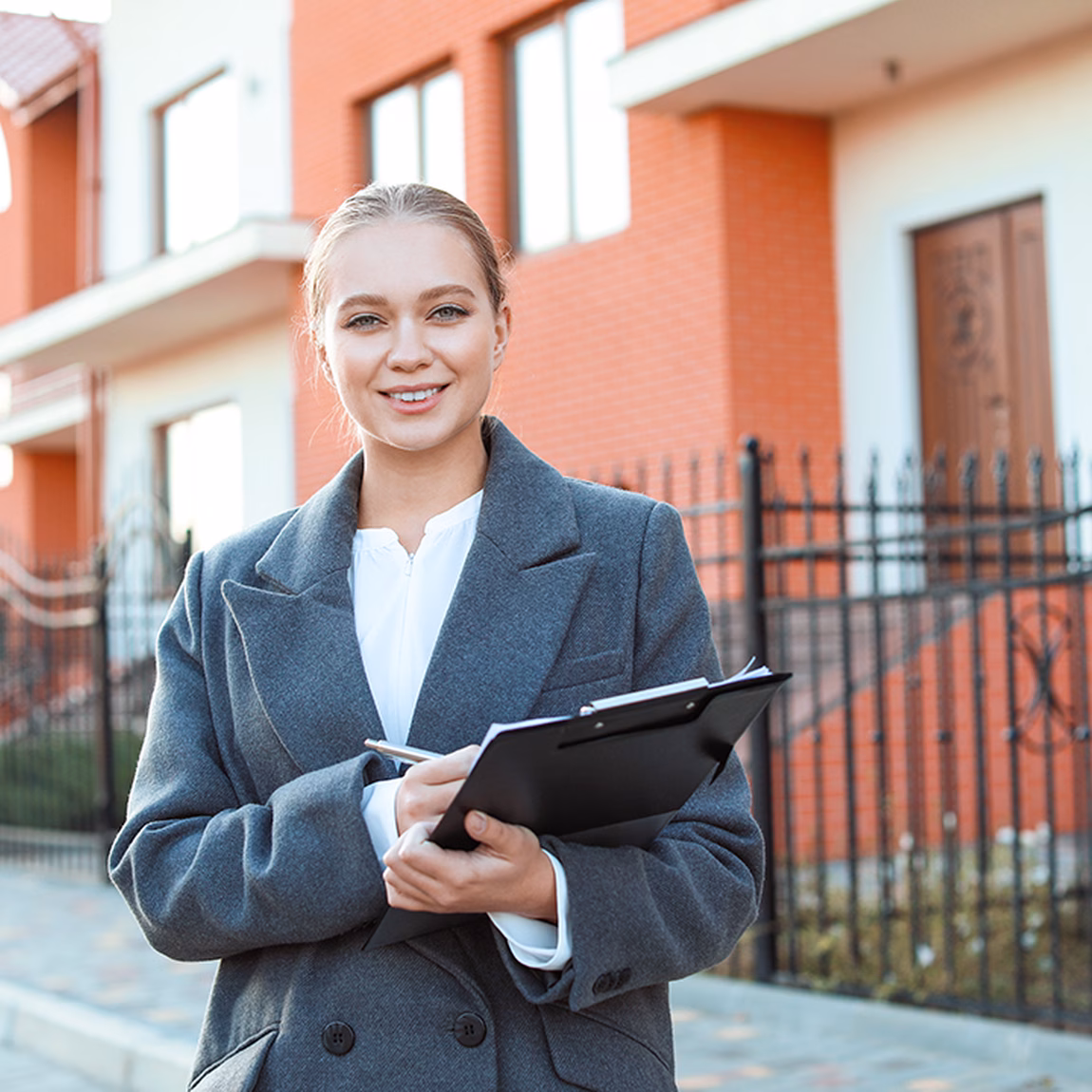 Professional met tablet staat voor een woonwijk met moderne woningen.