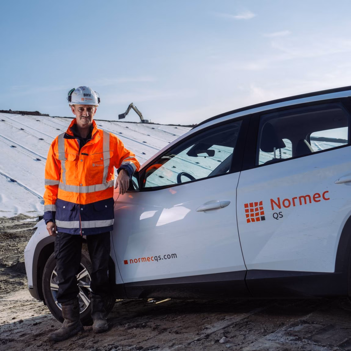 Een inspecteur staat bij een dienstvoertuig op locatie voor inspectie- en controlewerkzaamheden.
