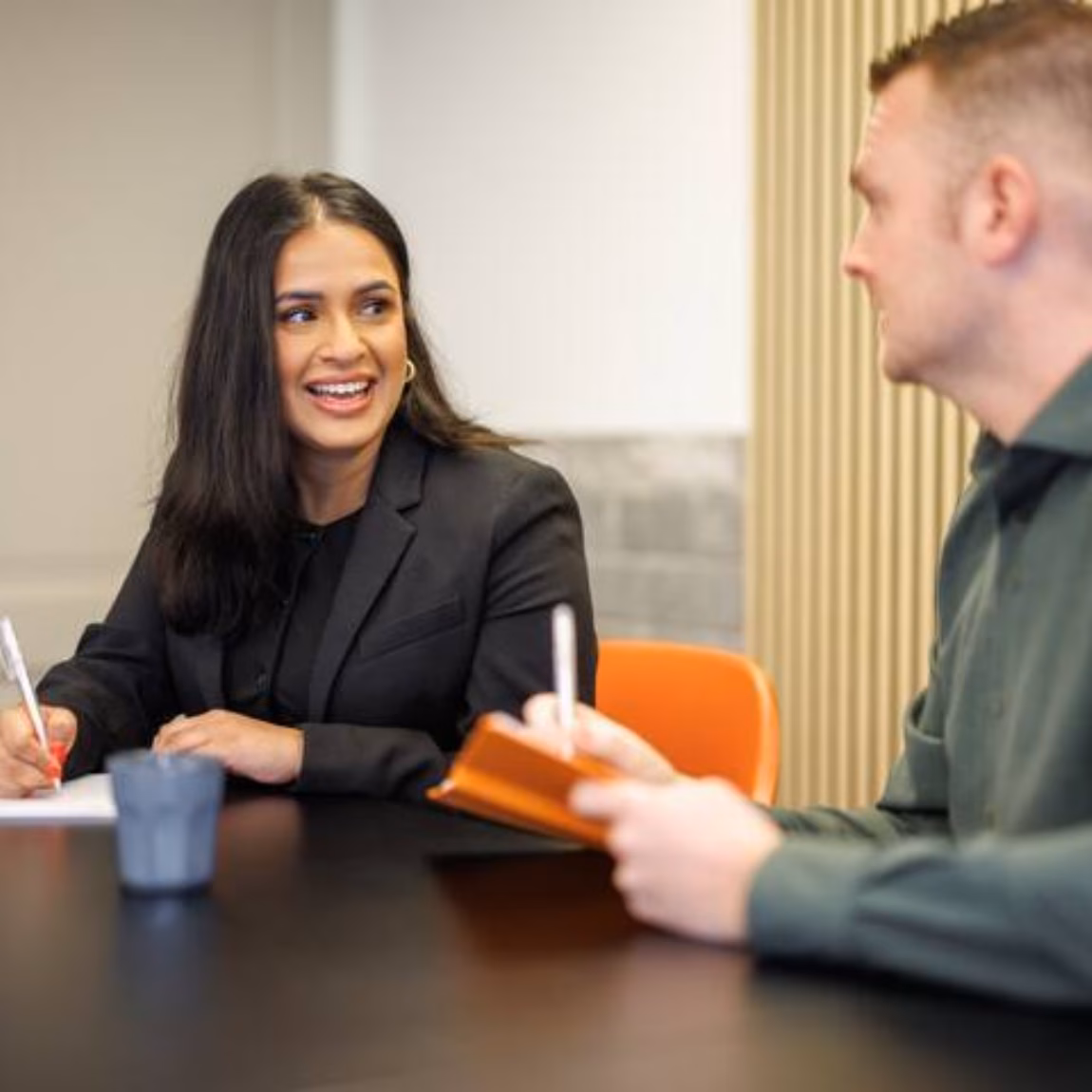 Twee collega’s bespreken notities tijdens een overleg in een vergaderruimte.