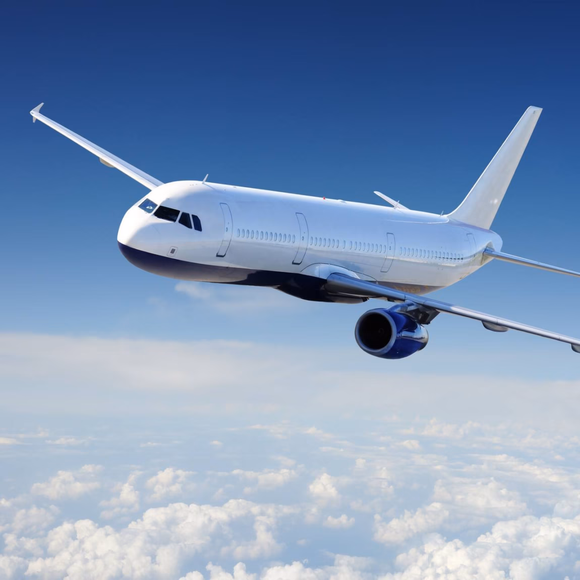 A passenger plane is flying at cruising altitude above a layer of clouds.