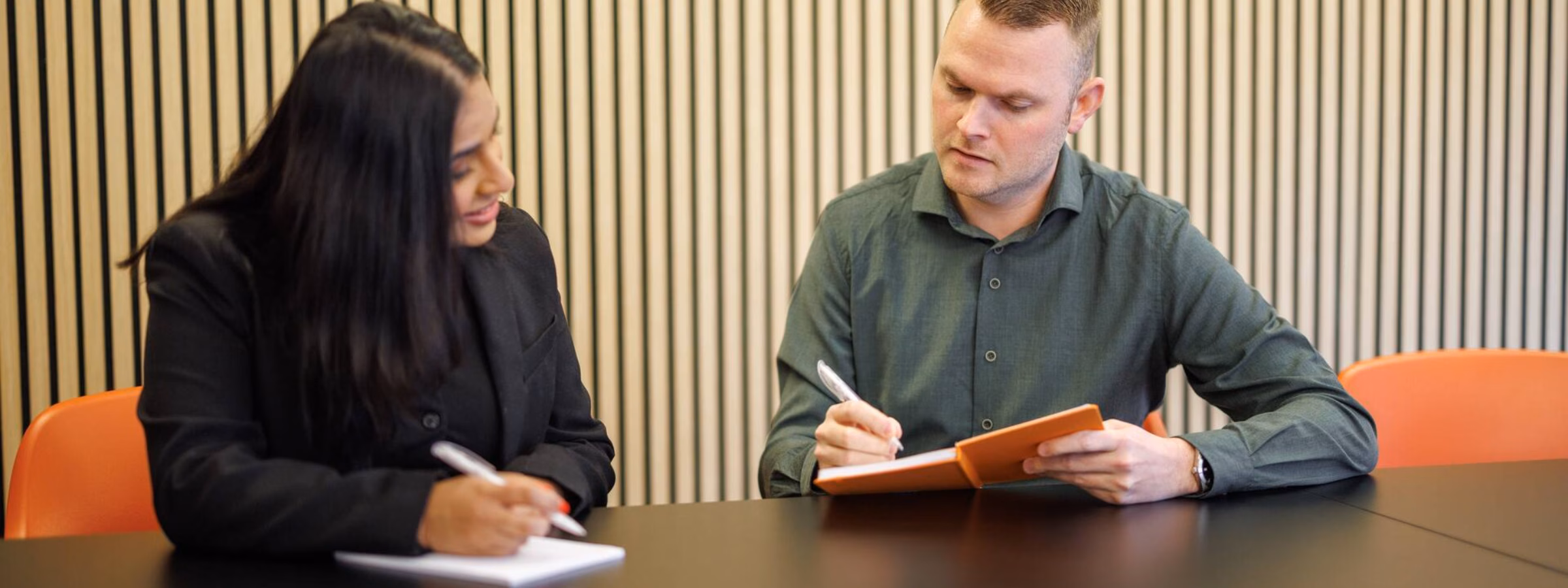 Zwei Mitarbeiter besprechen während einer Besprechung an einem Konferenztisch Unterlagen.