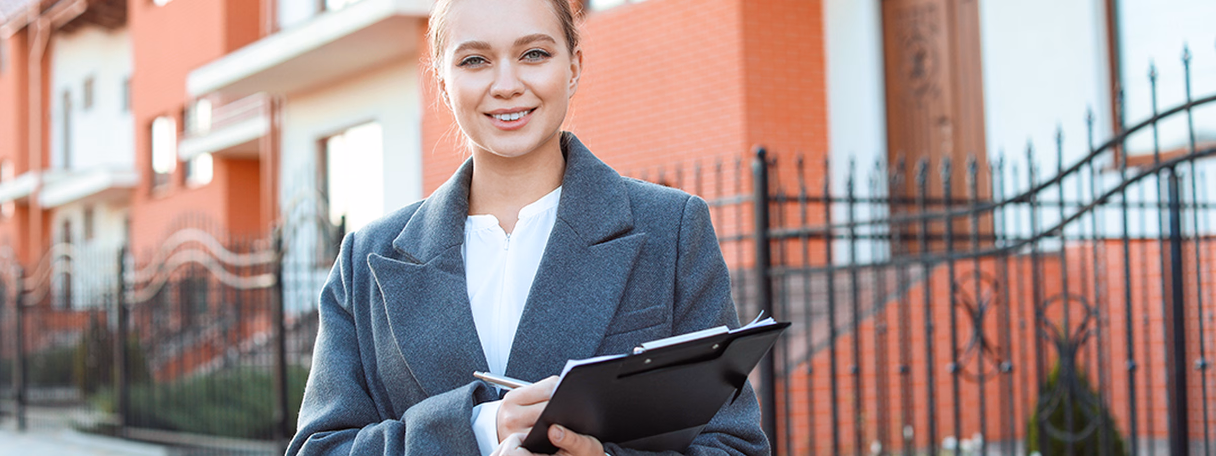 Professional met tablet staat voor een woonwijk met moderne woningen.