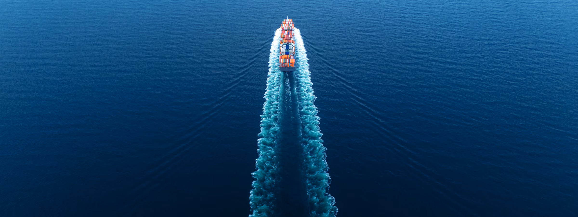 Ein Containerschiff transportiert Frachtcontainer auf offener See im Rahmen des internationalen Güterverkehrs.