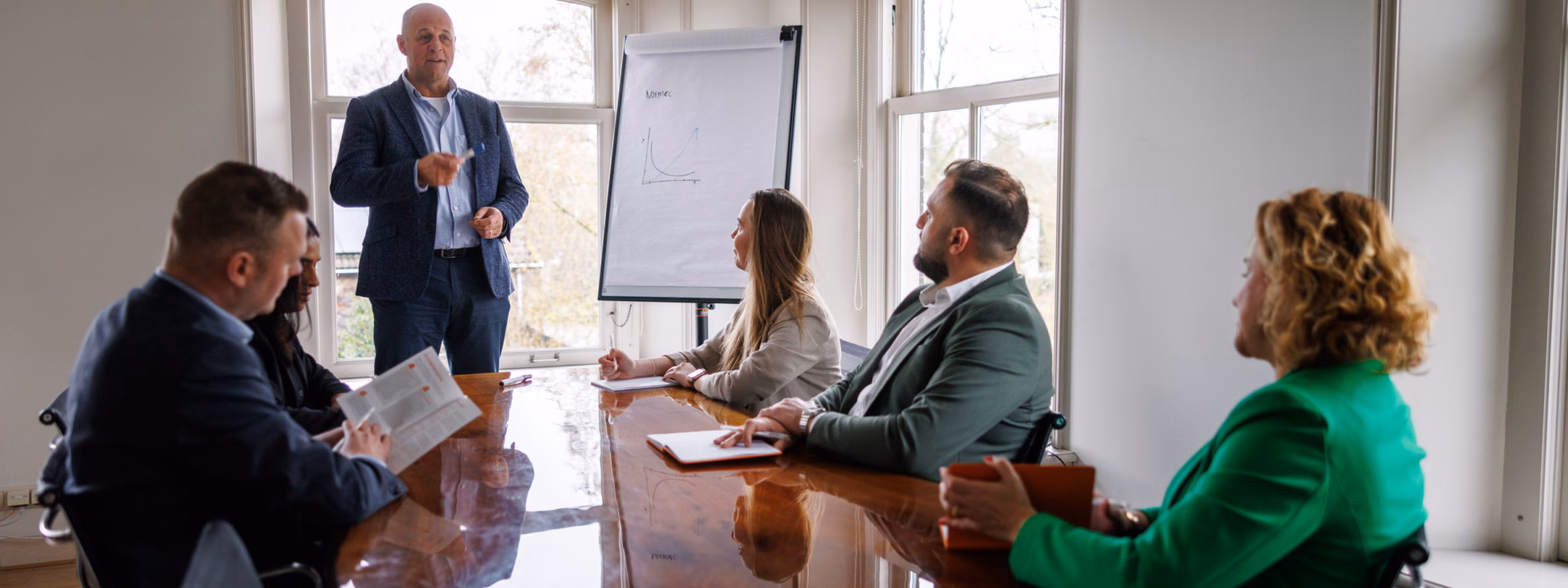 Professional geeft een presentatie aan collega’s tijdens een teamoverleg in een vergaderruimte.