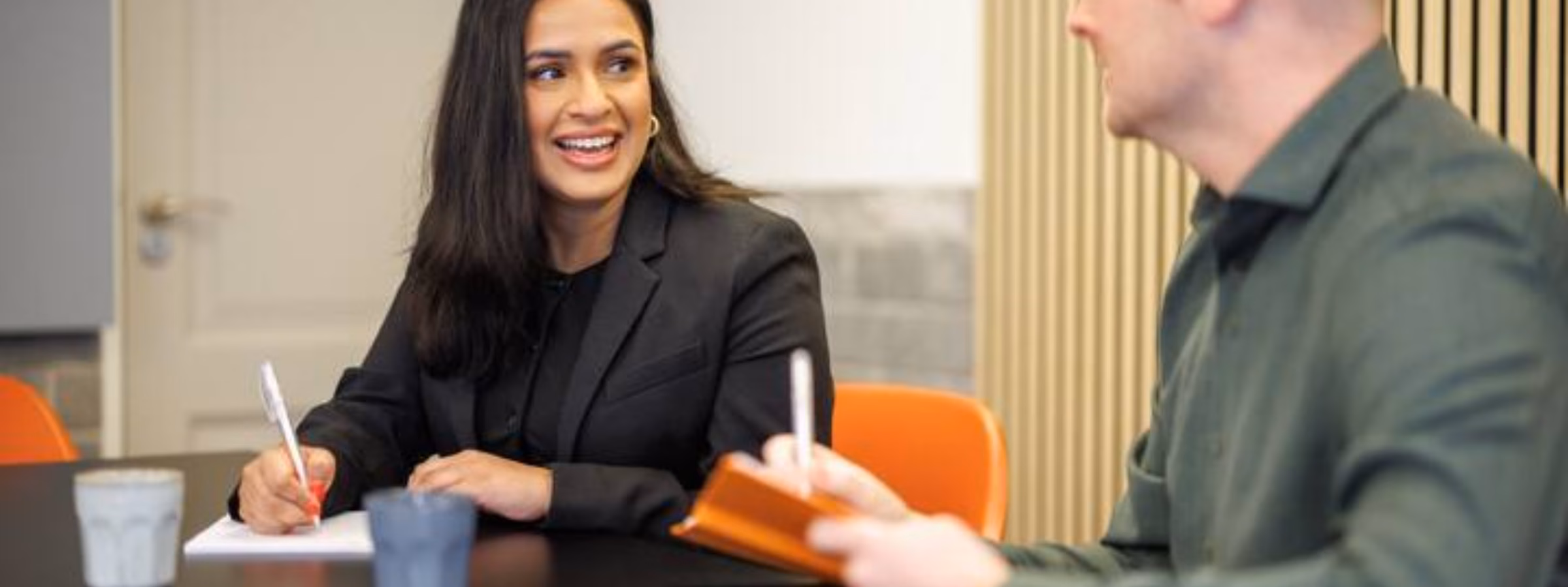 Twee collega’s bespreken notities tijdens een overleg in een vergaderruimte.