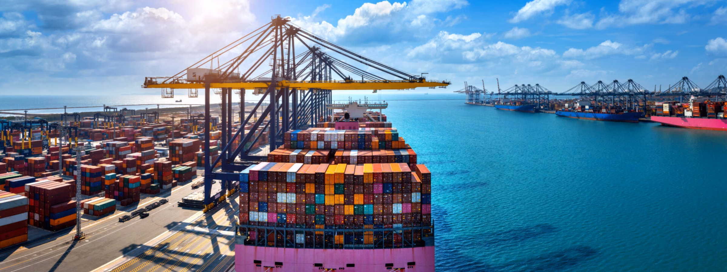 A container ship is being loaded and unloaded at a container terminal for international freight transport.