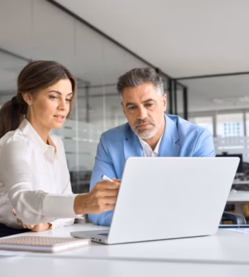 Two professionals are discussing data and documentation during a meeting at the office.