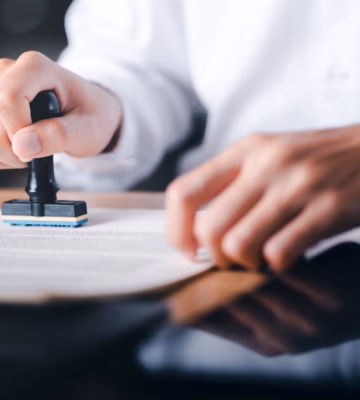 Im Rahmen eines Validierungs- oder Genehmigungsprozesses bringt ein Mitarbeiter einen offiziellen Stempel auf einem Dokument an.