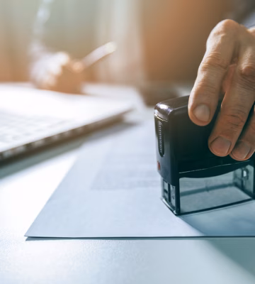 Zakelijke stempel wordt geplaatst op een document als onderdeel van een formele goedkeurings- of verificatieprocedure.