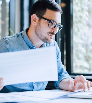 An employee reviews documents and digital data as part of an administrative process.