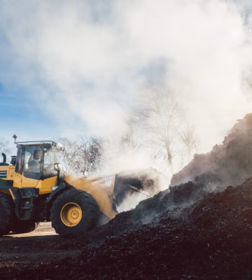 A wheel loader moves organic material during processing at a composting or storage site.