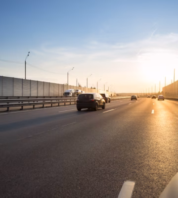 Verkeer rijdt over een snelweg met geluidswerende voorzieningen in een infrastructurele omgeving.