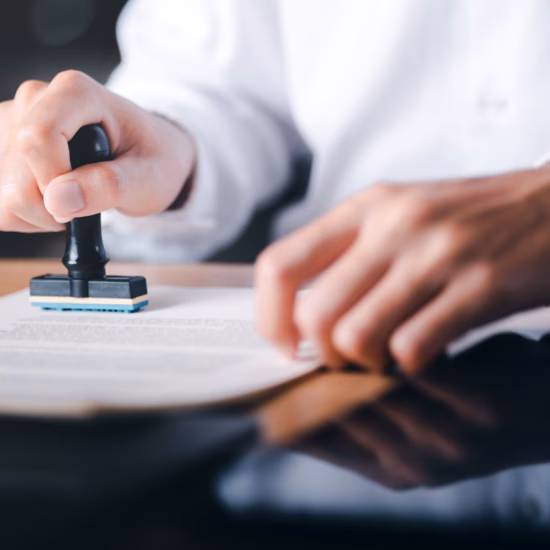 Im Rahmen eines Validierungs- oder Genehmigungsprozesses bringt ein Mitarbeiter einen offiziellen Stempel auf einem Dokument an.