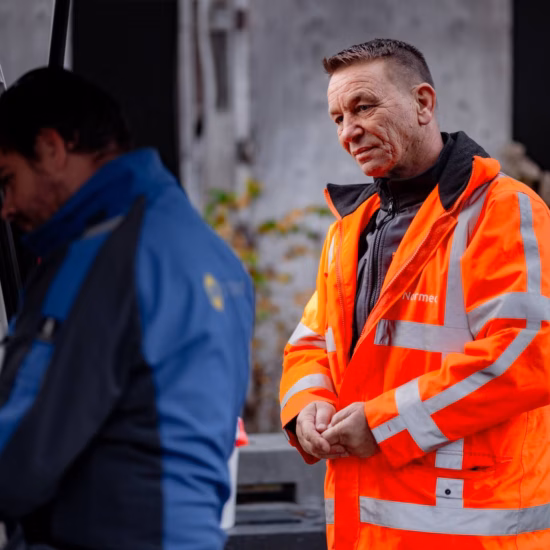 Aufsichtsperson in reflektierender Sicherheitskleidung bei Inspektionsarbeiten an einem Industriestandort.