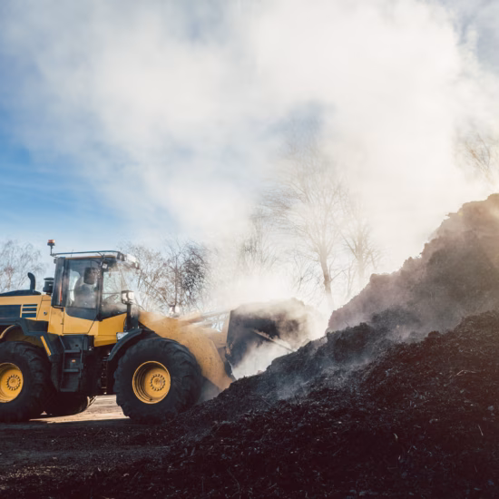 A wheel loader moves organic material during processing at a composting or storage site.