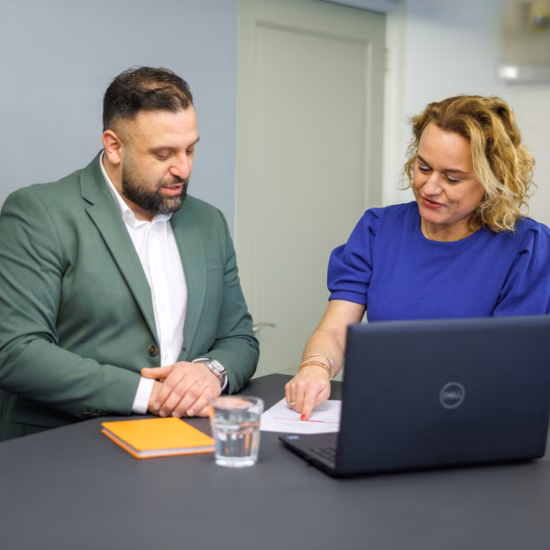 Man and woman looking at a laptop together while discussing and collaborating.