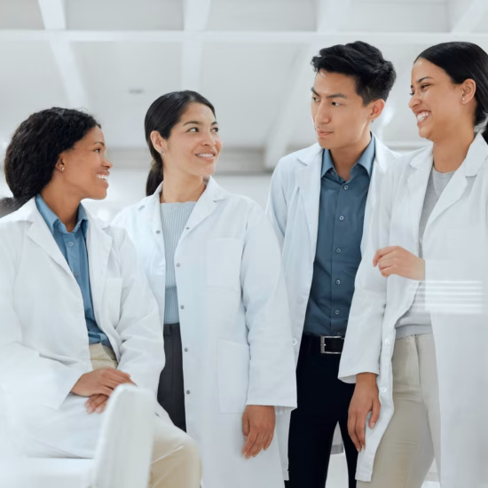 Staff members in lab coats consult with one another and work together in a professional research environment.