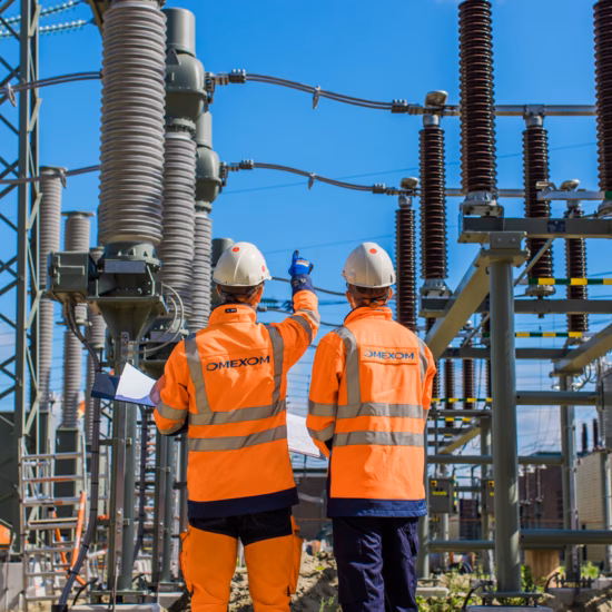 Two technicians are conducting an inspection of a high-voltage power supply system.
