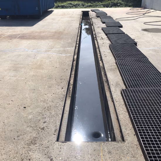 A drainage channel on a paved site is used to collect and discharge liquids.
