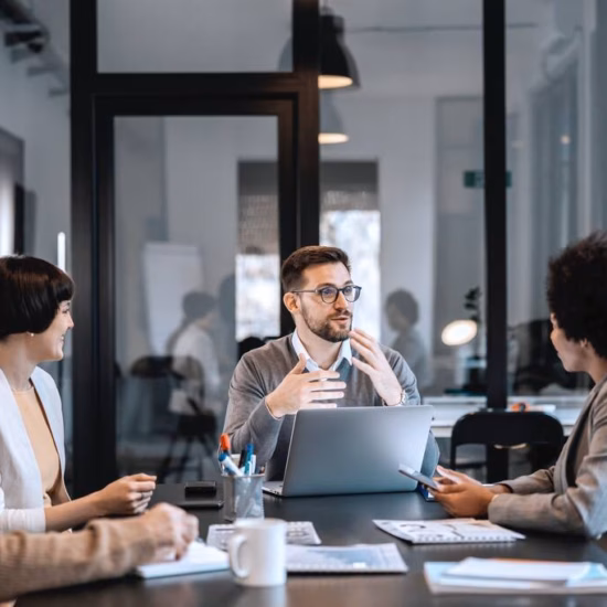 Team members discuss topics during a business meeting in an office setting.