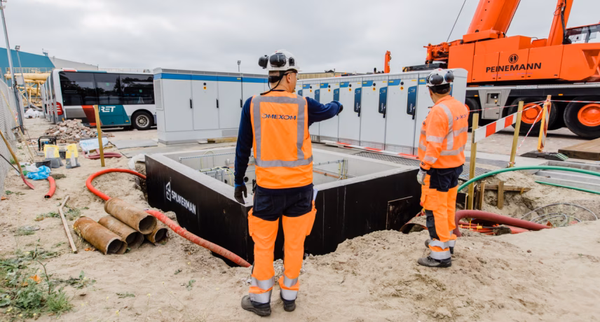 Employees supervise the installation and connection of an underground technical system.