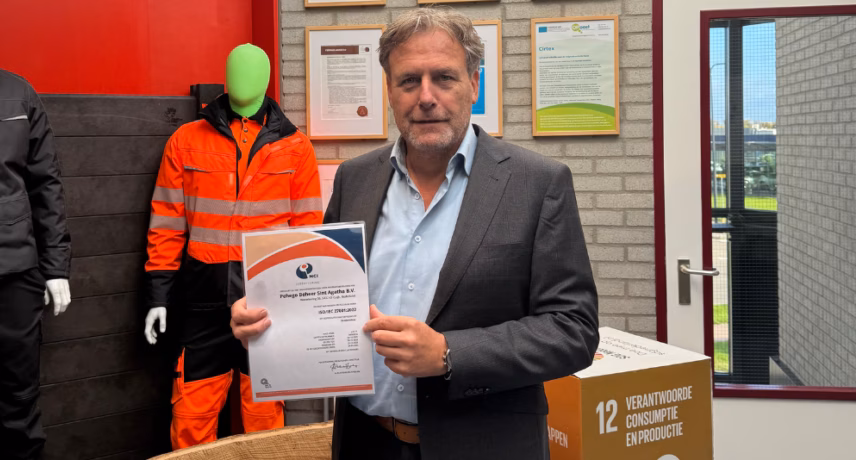 Eine Person hält während eines feierlichen Anlasses in einer Büro- oder Unternehmensumgebung ein Zertifikat in der Hand.