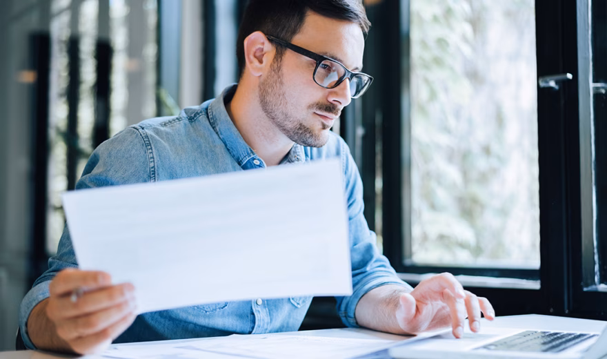 An employee reviews documents and digital data as part of an administrative process.