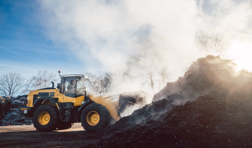 A wheel loader moves organic material during processing at a composting or storage site.