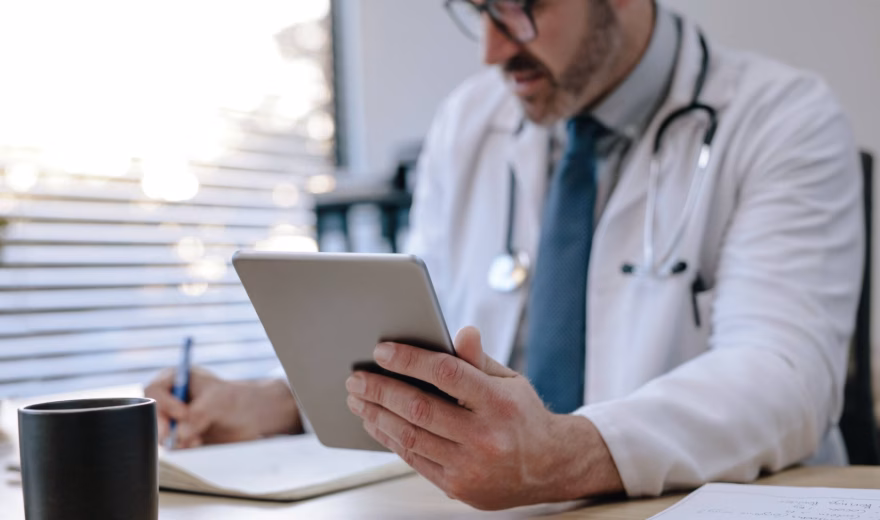 Ein medizinisches Fachpersonal nutzt ein Tablet bei der Überprüfung von Patientendaten in einer medizinischen Arbeitsumgebung.