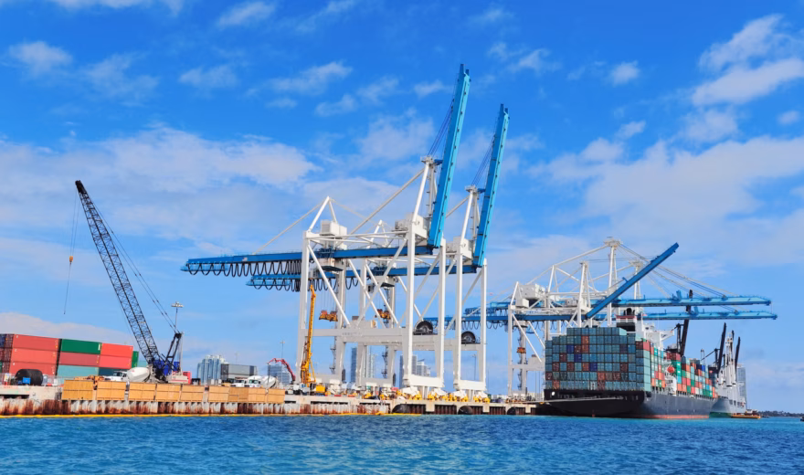 Ein Containerschiff wird an einem Containerterminal mit Umschlagkränen im Hafen be- oder entladen.