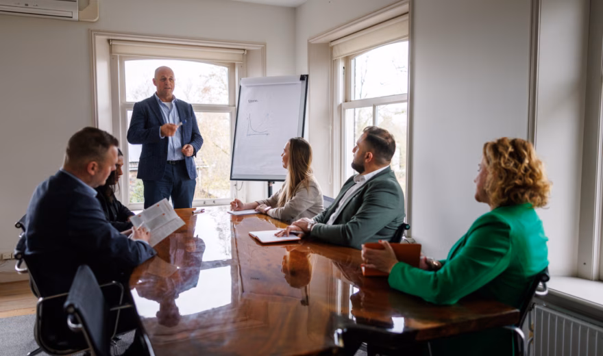 Professional geeft een presentatie aan collega’s tijdens een teamoverleg in een vergaderruimte.