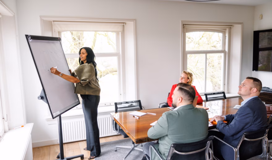 Professional presenteert informatie op een flip-over tijdens een teamoverleg in een vergaderruimte.