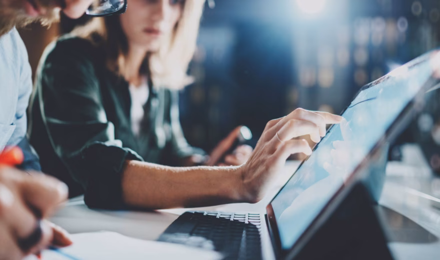 Employees analyze data and collaborate on digital processes using a laptop.