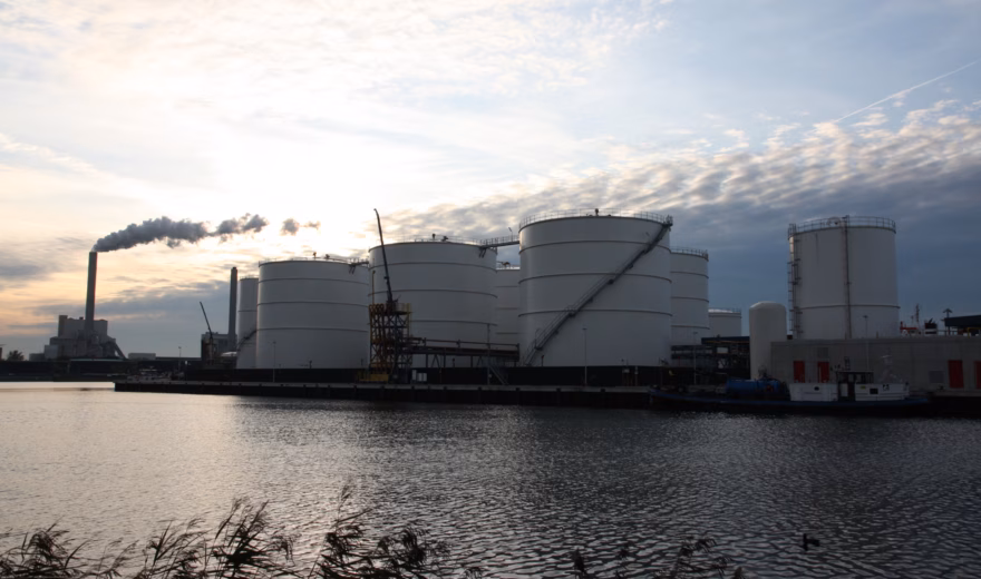Large storage tanks are part of an industrial site on the waterfront for the storage and processing of liquids.