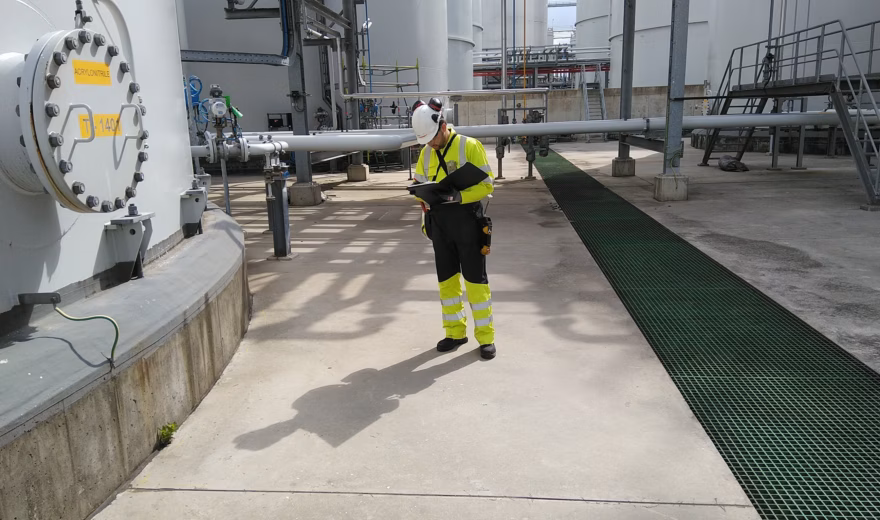 An inspector is conducting an inspection among storage tanks and process facilities at an industrial site.