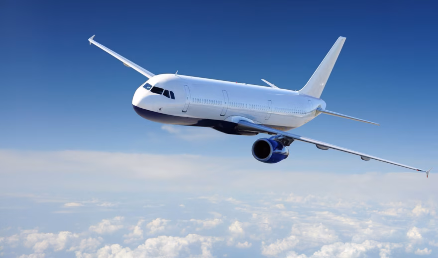 A passenger plane is flying at cruising altitude above a layer of clouds.